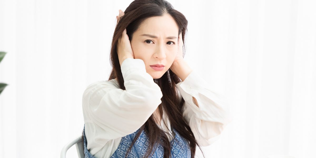 騒音に困って耳を塗いでいる入居者